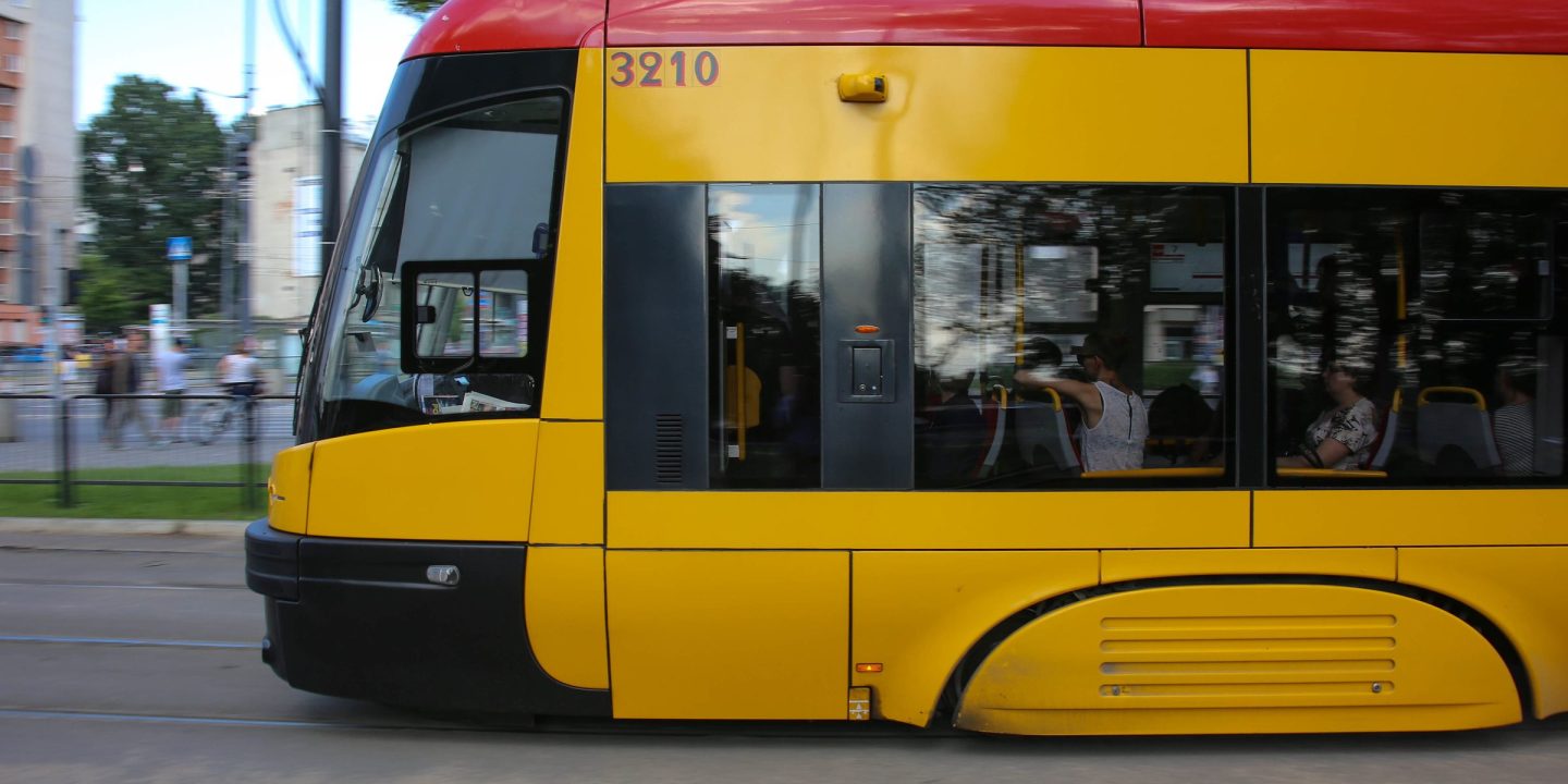 A modern yellow and red low-floor tram moving along a city street.