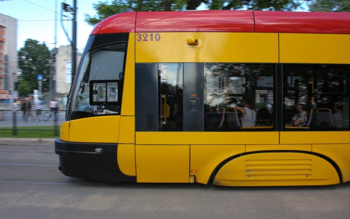 A modern yellow and red low-floor tram moving along a city street.