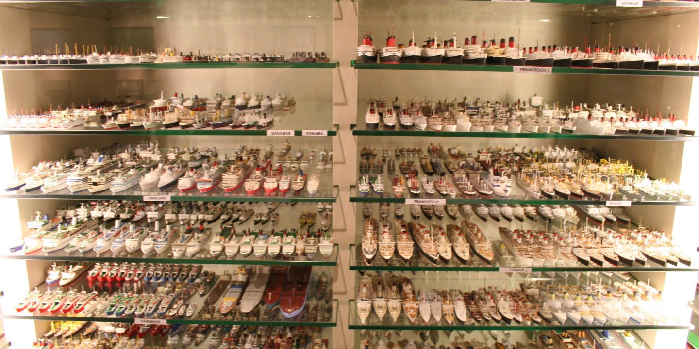 Glass shelves in a museum filled with hundreds of detailed miniature ship models.