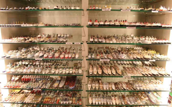 Glass shelves in a museum filled with hundreds of detailed miniature ship models.